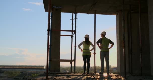 Строительный бизнес: концепция командной работы: молодой инженер, стоящий сзади и смотрящий на строительную площадку, в защитном шлеме . — стоковое видео