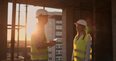 İki mühendis yavaş hareket bir gökdelen iş merkezinin inşası için gelecekteki proje hakkında konuşuyor ve gün batımı el sallayarak