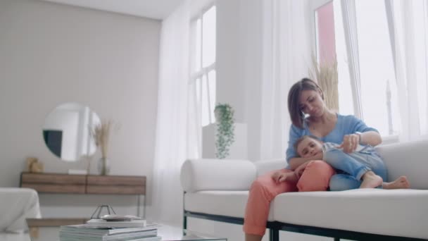 Madre e hijo usando la tableta mirando la pantalla y hablando en el sofá en la casa acogedora . — Vídeo de stock