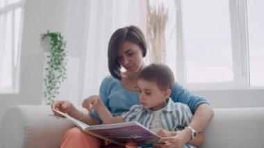 Güvenli otururken küçük sevimli çocuk anne ile kitap okuma portre.