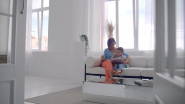 Sevgi dolu bir anne oğlu evde kanepede konuşma holding kitap okumak için öğretim.