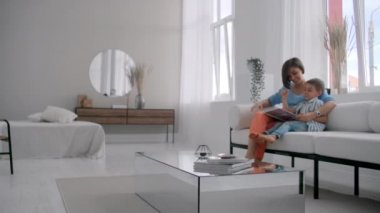 Mutlu anne ve çocuk oğlu okuma kitap yatakta gülüyor. Mutlu aile anne ve çocuk oğul okuma tutan kitap yatakta yatarken, gülümseyen anne bebek bakıcısı.