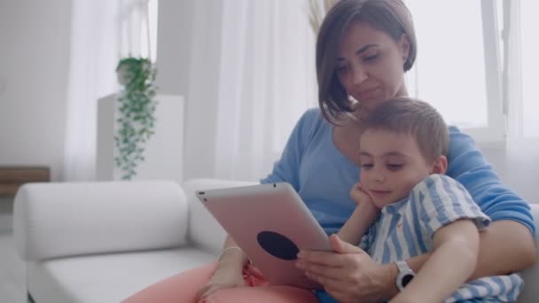 Madre e hijo jugando con la tableta digital en casa. Joven madre con sus 5 años sonriendo con la tableta digital en casa . — Vídeos de Stock