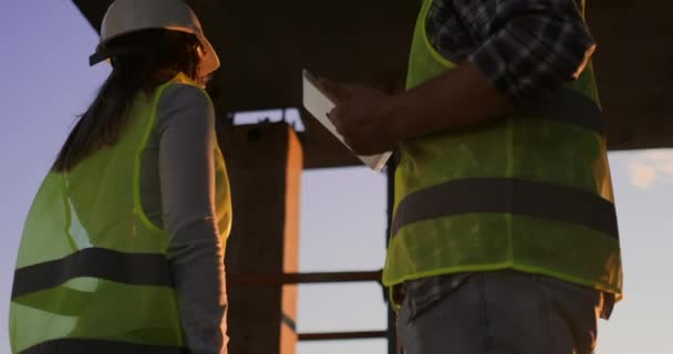 Guapos trabajadores de la construcción, hombres y mujeres, con cascos y chalecos protectores, se dan la mano mientras trabajan en el centro de oficinas . — Vídeo de stock