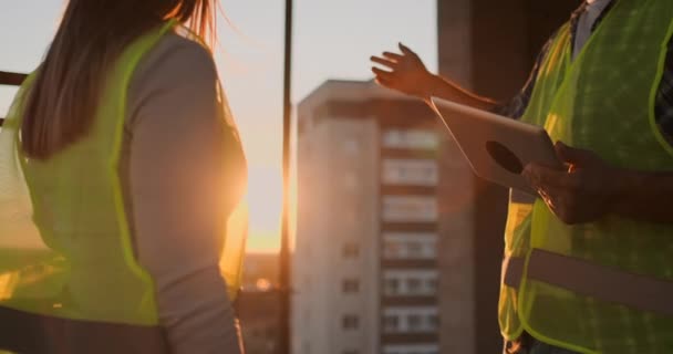 Il rallentatore di due ingegneri sta parlando del futuro progetto per la costruzione di un business center grattacielo e stringendo la mano al tramonto — Video Stock