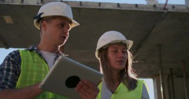 İnşaat sitesi takım veya mimar ve kurucu veya işçi kask ile bir iskele inşaat planı veya plan veya kontrol listesi üzerinde tartışmak.