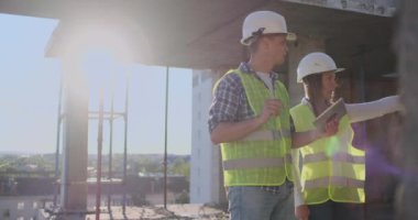 İnşaat sitesi takım veya mimar ve kurucu veya işçi kask ile bir iskele inşaat planı veya plan veya kontrol listesi üzerinde tartışmak.