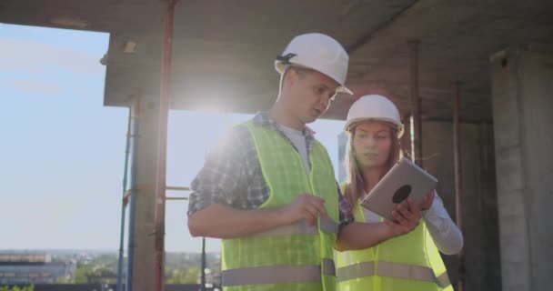 Команда или архитектор и строитель или рабочий в шлемах обсуждают на строительном эшафоте план или чертеж или контрольный список . — стоковое видео