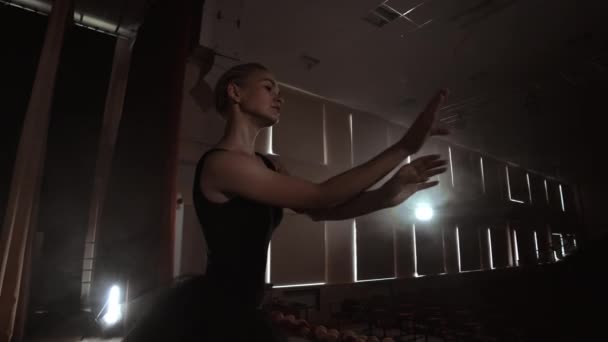 Αργή κίνηση: το μπαλέτο σε μαύρο φόρεμα εκτελεί περιστροφές και χορεύει χαριτωμένες κινήσεις κάνοντας πρόβα ένα σόλο πρόγραμμα. Η φωτογραφική μηχανή μετακινείται σε — Αρχείο Βίντεο