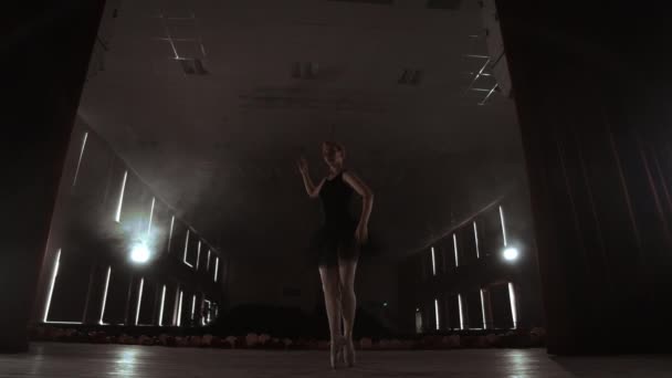 Slow motion: prima ballerina i en svart klänning utför rotationer och graciösa danssteg. Kameran rör sig på Gimbal. — Stockvideo