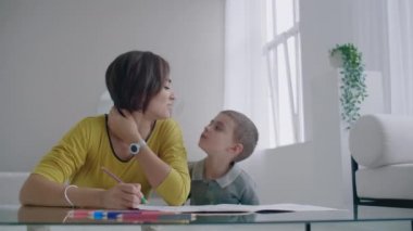 Oğlumla işaretleri ile ailesi tasvir kağıt üzerine çizim yerde yatarken bir sıcak kazaklı güzel genç anne. Çocuk öğrenir çizmek için.