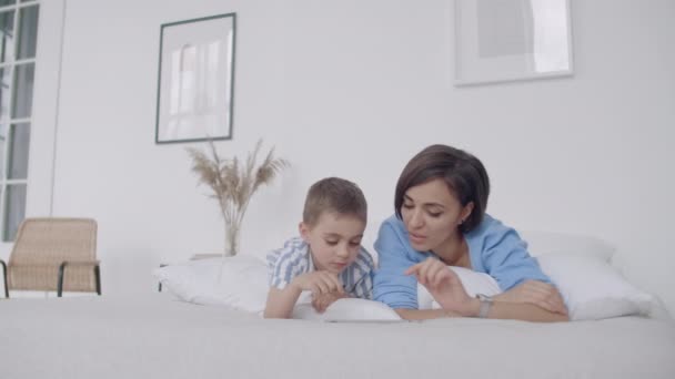 Madre e figlio utilizzando tablet digitale in camera da letto a casa. Vista frontale di felice madre e figlio caucasico utilizzando tablet digitale in camera da letto a casa . — Video Stock