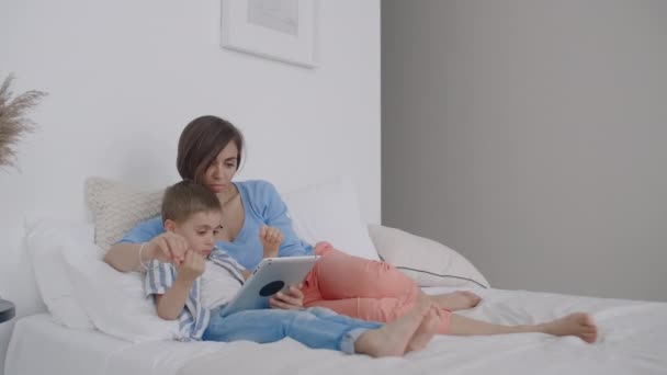 Lycklig familj mor och barn son med tablett på kvällen. Lycklig familj mor och barn son med tablett på kvällen innan sängen. — Stockvideo