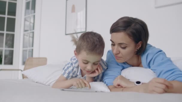 Gelukkige familie moeder en kind zoon met Tablet in de avond. Gelukkige familie moeder en kind zoon met Tablet in de avond voor het bed. — Stockvideo