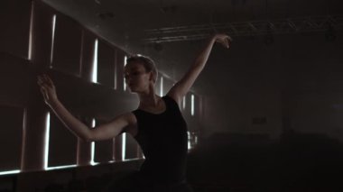Yavaş hareket: Prima Ballet bir solo performans ışık siyah bir elbise duman tiyatro sahnesinde ayakta prova