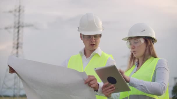Engineering werken aan hoogspannings toren, Controleer de informatie op de Tablet computer twee werknemers man en vrouw. — Stockvideo