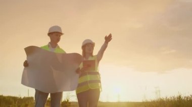 Mühendis ve tablet Pc ve çizimler ile süpervizör hatları ve iletim kuleleri hakkında ve kasaba ve şehirler için genişleme planı ve ulaşım enerjisi tartışmak.