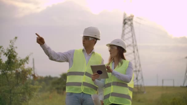 Ingenieure in Uniform arbeiten mit einem Laptop in der Nähe von Übertragungsleitungen — Stockvideo