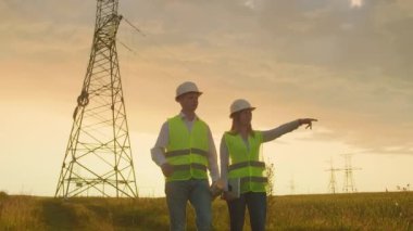 Yüksek gerilim kulesi üzerinde çalışan mühendislik, tablet bilgisayar iki çalışanı erkek ve kadın bilgi kontrol edin.