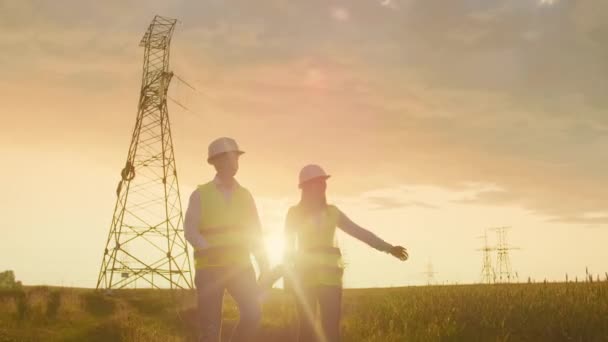 Ingenieros de coworking con tabletas en planta solar. Hombres y mujeres adultos con gorras duras usando tabletas mientras están al aire libre en la plataforma del transformador. Transporte de energía limpia — Vídeos de Stock