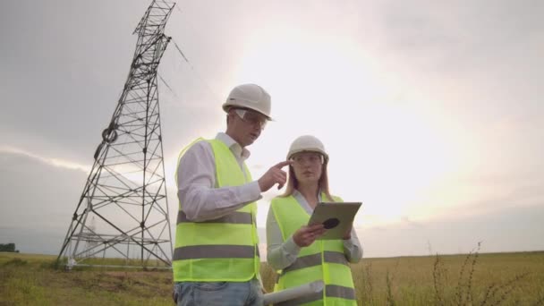 Ingeniero y supervisor con tableta PC y los dibujos son sobre líneas y torres de transmisión y discutir el plan de expansión y energía de transporte para pueblos y ciudades . — Vídeo de stock