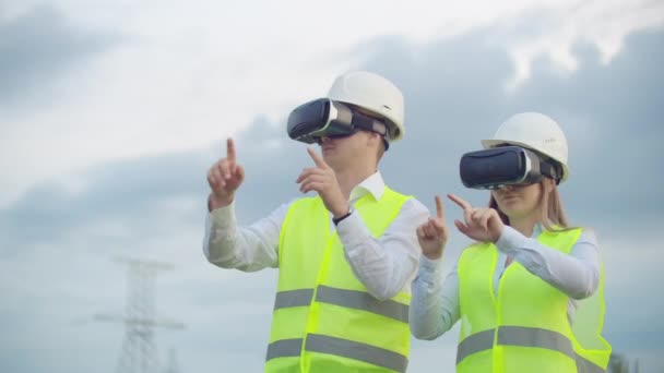 High-voltage power lines under the control of two engineers using virtual reality to control power. Alternative energy sources in a modern city — Stock Video
