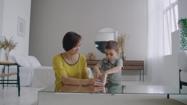 Счастливые и смеющиеся мама и сын играют вместе с Лизуном, жидкой растяжимой игрушкой — стоковое видео