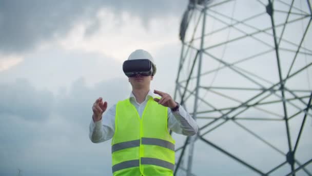 Linhas de alta tensão controladas por um engenheiro masculino usando realidade virtual para controlar a potência. Fontes de energia alternativas em uma cidade moderna . — Vídeo de Stock