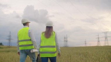 Geri iki Mühendis ve bir tablet Pc ile denetleyici ve çizimler hatları ve iletim kuleleri hakkında ve genişleme planı ve kasaba ve şehirler için ulaşım enerjisi tartışmak