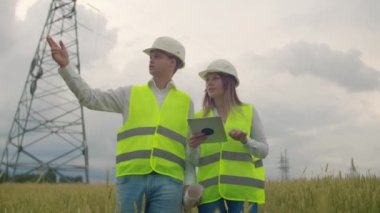 Güç iletim hattının yakınındaki tarlalarda bir elektrikçi. Elektrikçi elektrik hatları dikme sürecini yönetir. Kasklı tamirci.