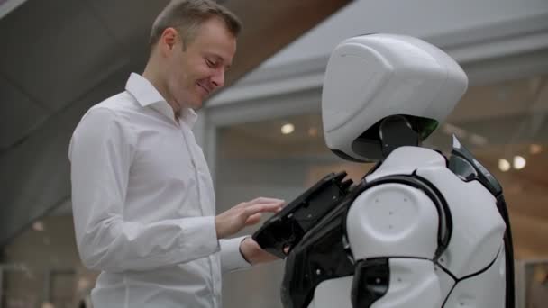 A bevásárlóközpontban lévő férfi egy robottanácsadóval kommunikál. Modern üzlet és robot eladó. Robot segít az ember a Mall — Stock videók