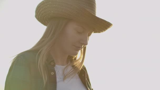 Une agricultrice portant une chemise à carreaux avec un ordinateur tablette à la main traverse un champ de blé au coucher du soleil, vérifiant. La qualité et la maturité de la culture . — Video