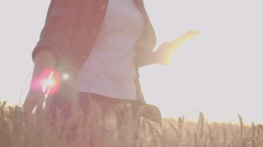 Genç kız çiftçi günbatımı arka plan buğday alanında ekose gömlekli. Kız bir tablet kullanır, hasat planları