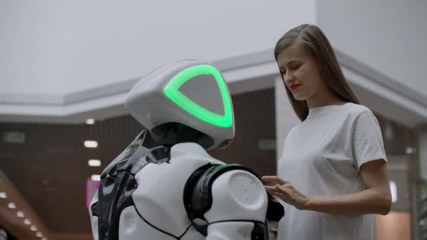 Een vrouwelijke programmeur test de robot voor de mogelijkheid om te communiceren met gebruikers. Het gebruik van een robot assistent op kantoor. De robot geeft hulp aan het meisje. — Stockvideo