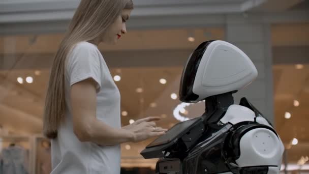 En kvinnlig programmerare testar roboten för förmågan att interagera med användare. Användning av en robot assistent på kontoret. Roboten ger hjälp till flickan. — Stockvideo