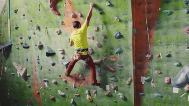 Escalada conceito de atividade esportiva: Homem alpinista na parede. Conceito de atividade esportiva de escalada interna: homem alpinista na parede de escalada artificial — Vídeo de Stock