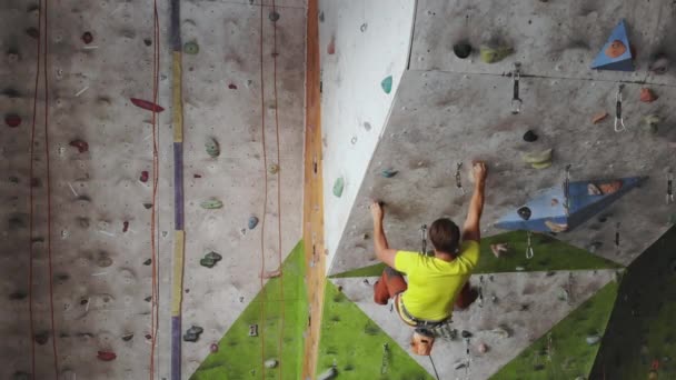 Fiatal férfi rock hegymászó a hegymászás Inside hegymászás Gym. karcsú csinos férfi gyakorlása a beltéri hegymászás Gym Wall — Stock videók