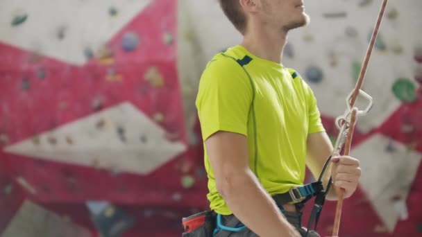 Homme assumant un autre grimpeur sur un mur d'escalade intérieur — Video