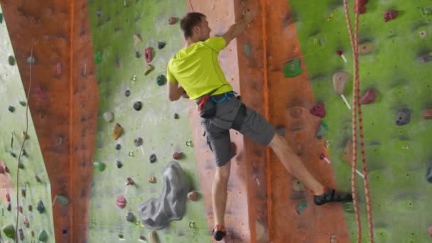 Escalada concepto de actividad deportiva: Hombre escalador en la pared. Concepto de actividad deportiva de escalada en interiores: escalador de hombre en un muro de escalada artificial — Vídeo de stock