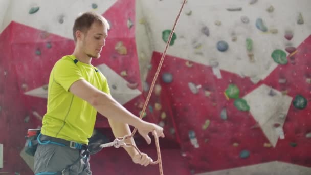 Närbild av klättrare man belaying annan klättrare mot en vägg med krokar. — Stockvideo