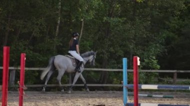 Profesyonel kız binici bir at üzerinde dörtnala. Gün batımında arenada ata binen kız. At toynak çok toz oluşturur. Rekabetçi binici eğitim atlama