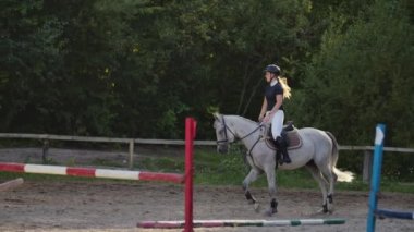 Profesyonel kız binici bir at üzerinde dörtnala. Gün batımında arenada ata binen kız. At toynak çok toz oluşturur. Rekabetçi binici eğitim atlama