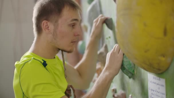 Ritratto di un arrampicatore che si prepara a scalare la parete della sala per calpestarsi le mani e arrampicarsi sulla parete con assicurazione al rallentatore — Video Stock