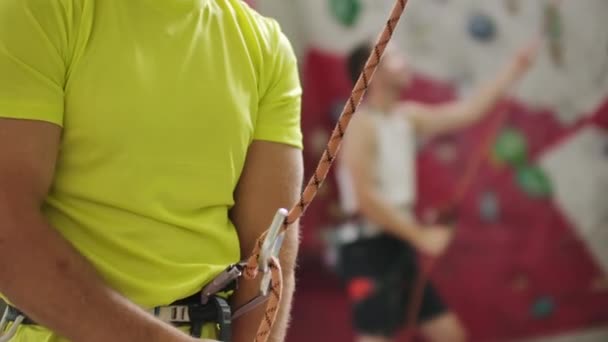 Close-up of Climber man belaying another climber against a wall with hooks. — Stock Video