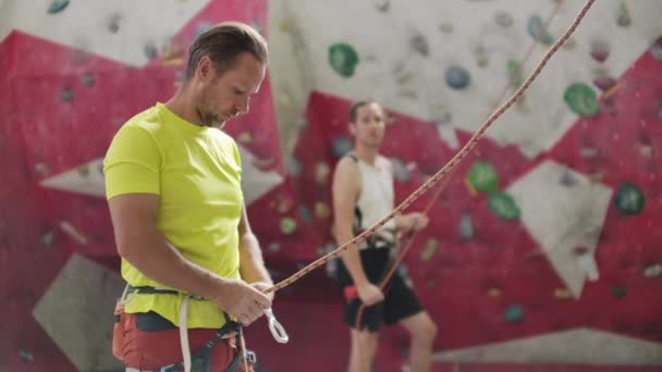 Dağcı adamın yakın çekim kancaları ile bir duvara karşı başka bir dağcı belaying. — Stok video