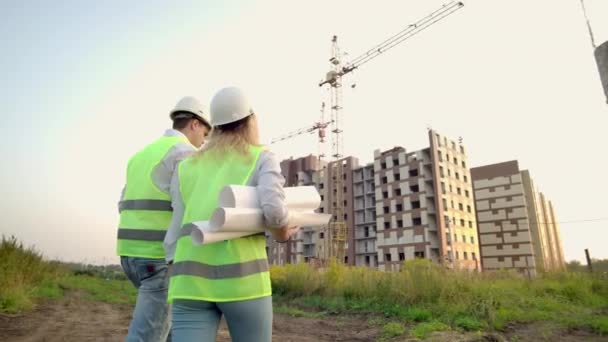 Inženýrovi a inspektorkou na staveništi se obrátily stavební modrotisky a technické výkresy procházky a diskuse — Stock video