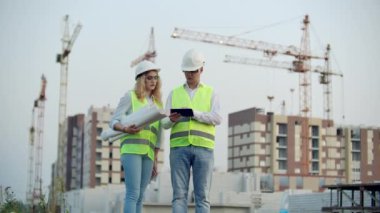 İş, inşaat, sanayi, teknoloji ve insan kavramı - şantiyede inşaatçılar çizimleri ile kadın ile birlikte tablet pc bilgisayar ile hardhat gülümseyen oluşturucu.