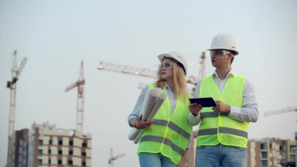 Costruttore e ingegnere camminano lavorando sul cantiere utilizzando tablet e stampa — Video Stock