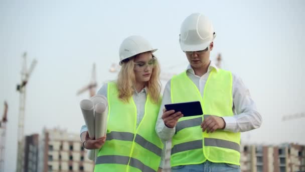 Будівельний менеджер та інженер ходять Робота на будівельному майданчику за допомогою планшета та друку — стокове відео
