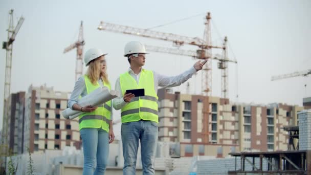 Homme ingénieur adulte et femme architecte utilise une tablette en fonctionnement. Ecrit un message ou vérifie un dessin. Dans le contexte se construit . — Video